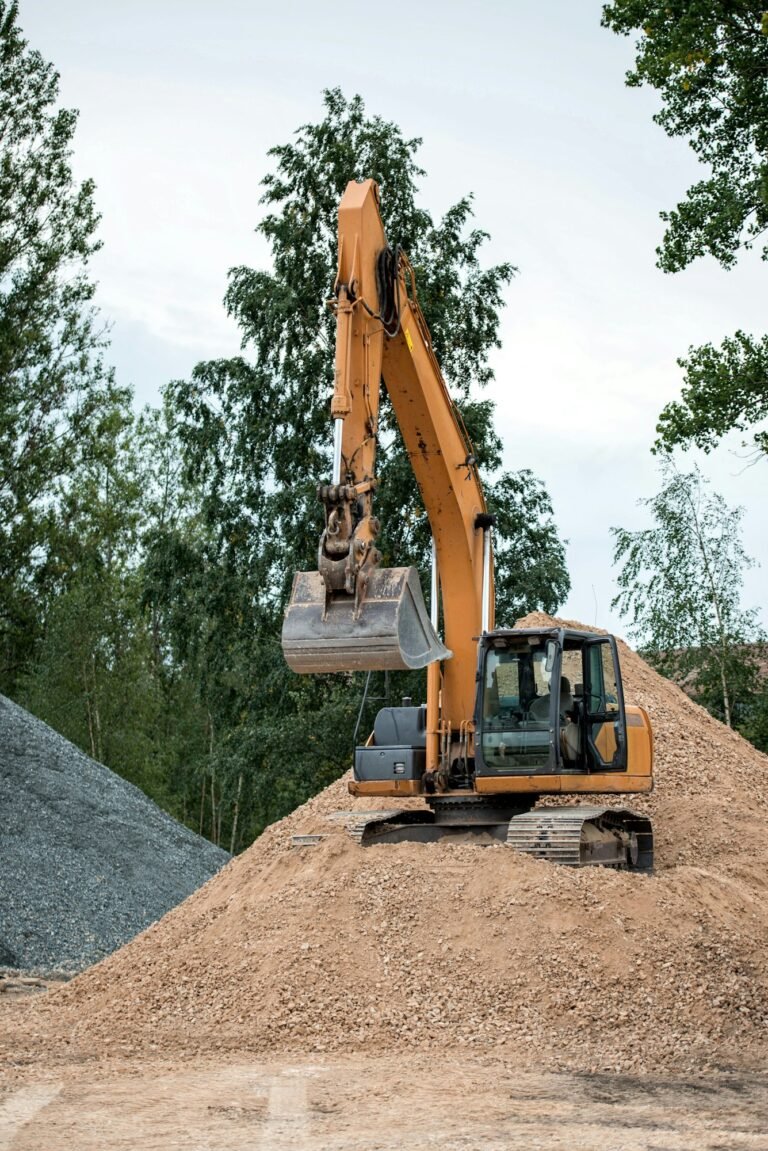 Yellow excavator on gravel pile.